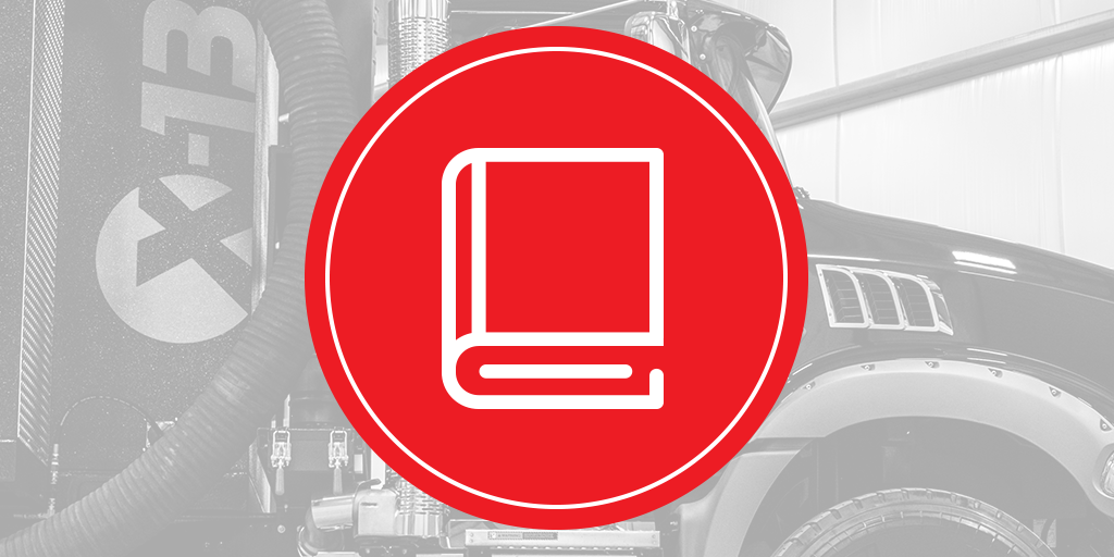 Red circular icon with white book/manual symbol over a grayscale X-Vac hydro-excavation truck showing vacuum hose and fender